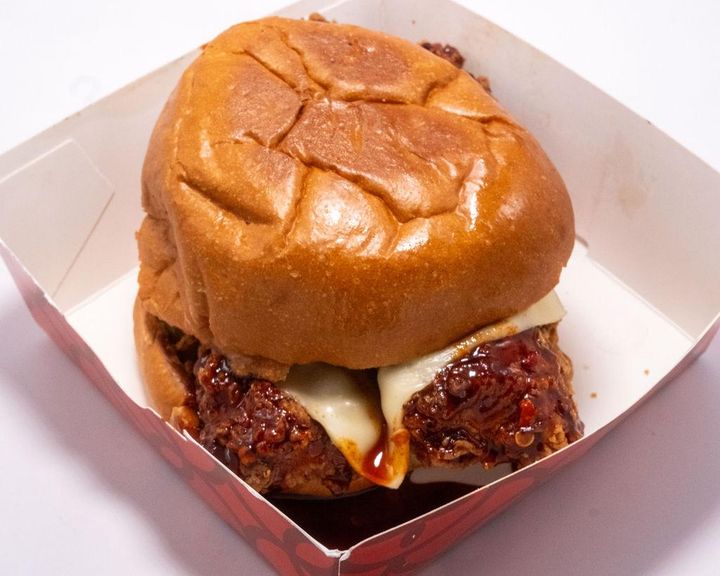 A crispy spicy Korean fried chicken sandwich topped with fresh greens and signature sauce.